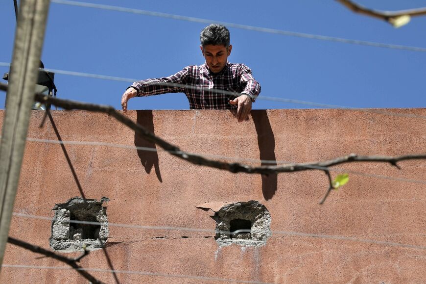 A man shows a wall damaged in the fighting in Hiror, near the Iraqi border with Turkey