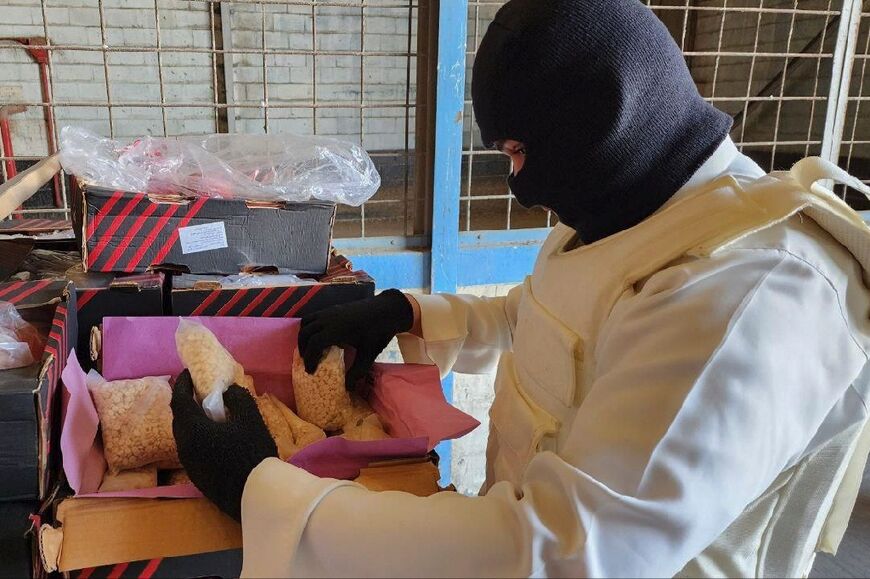 A balaclavaed Saudi police officer inspects the haul from a drugs raid in Jeddah 