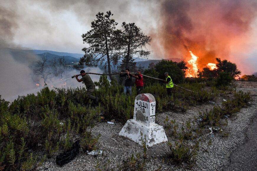 Firefighters battle near the town of Melloula in northwestern Tunisia close to the border with Algeria on July 24, 2023