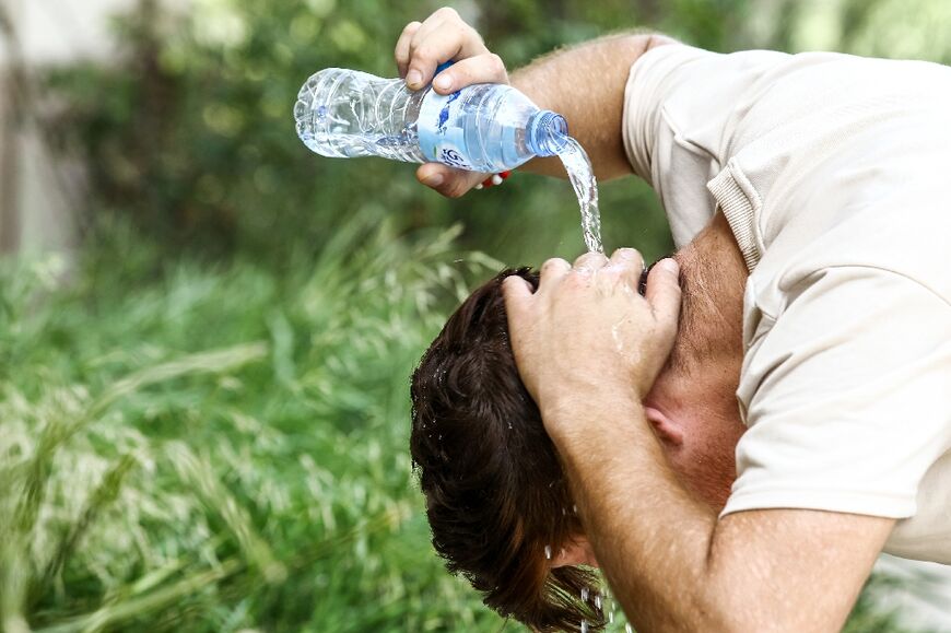 A man pours water on his head to cool off in Algiers during a heat wave