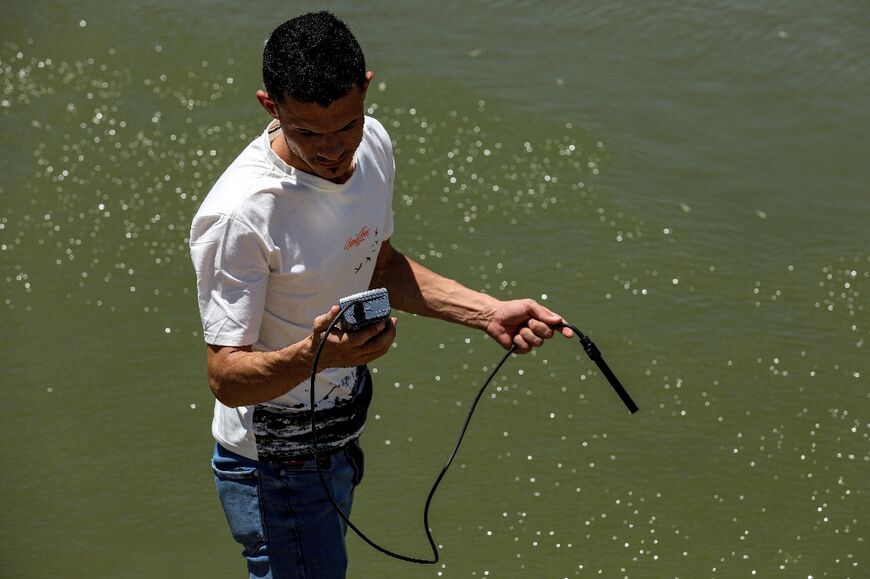 An Iraqi government official measures the oxygen level and salinity of the water of the Amshan river