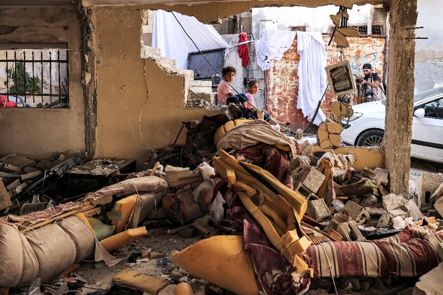 Children sit amid the rubble and broken furniture of a destroyed flat in Jenin 