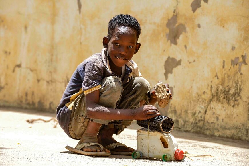 A displaced boy plays with a homemade vehicle toy at his makeshift shelter in al-Hasaheisa