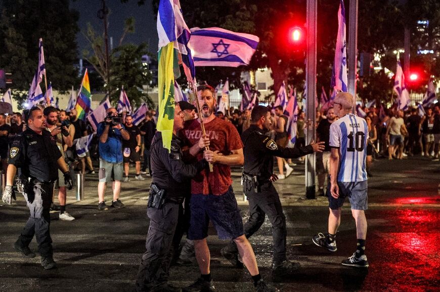 An Israeli riot policeman restrains a demonstrator at a protest in Tel Aviv against the controversial judicial reform vote