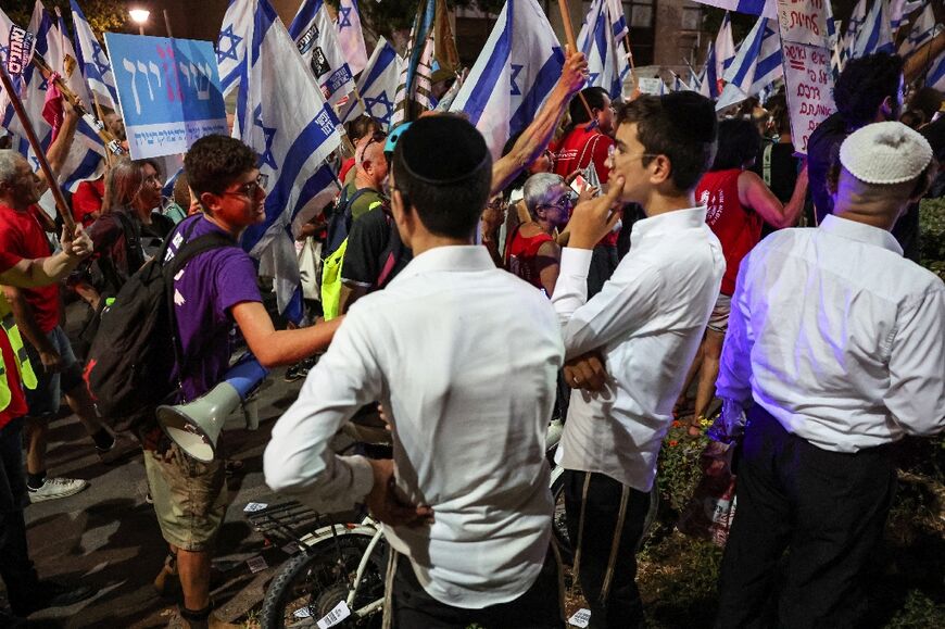 Ultra-Orthodox Jewish residents look on as the activists pass by