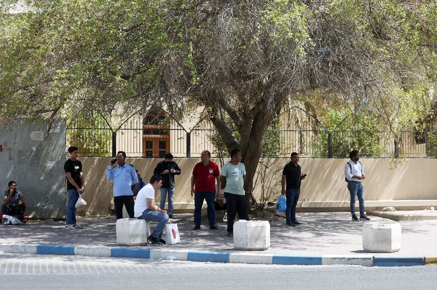 Workers shelter from the blazing sun in Kuwait City