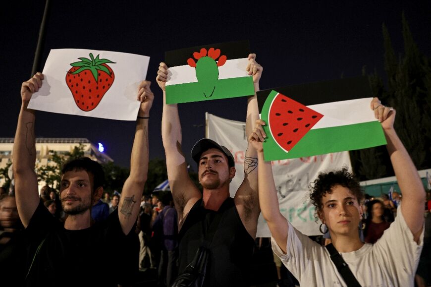 Demonstrators hold placards in the colours of the Palestinian flag during a protest against the Israeli government's judicial overhaul in Tel Aviv