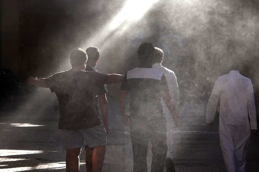 People are cooled by a mist dispenser at Kuwait City's al-Mubarakiya market