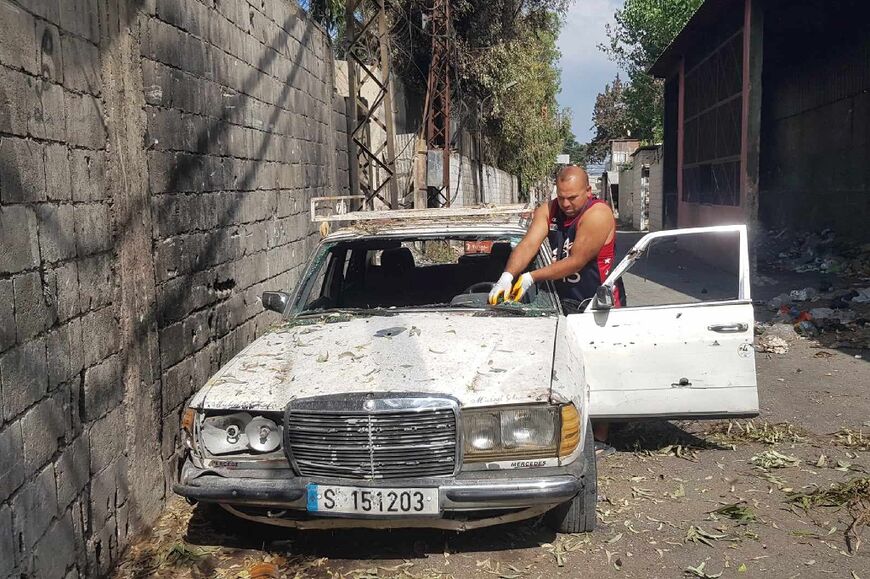 A man clears broken glass from a car damaged in the fighting