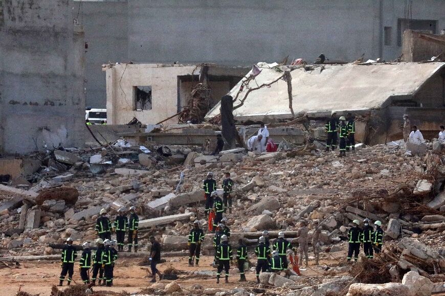 Emergency teams gather amid the rubble of buildings flattened by the devastating flash flood which hit the Libyan city of Derna