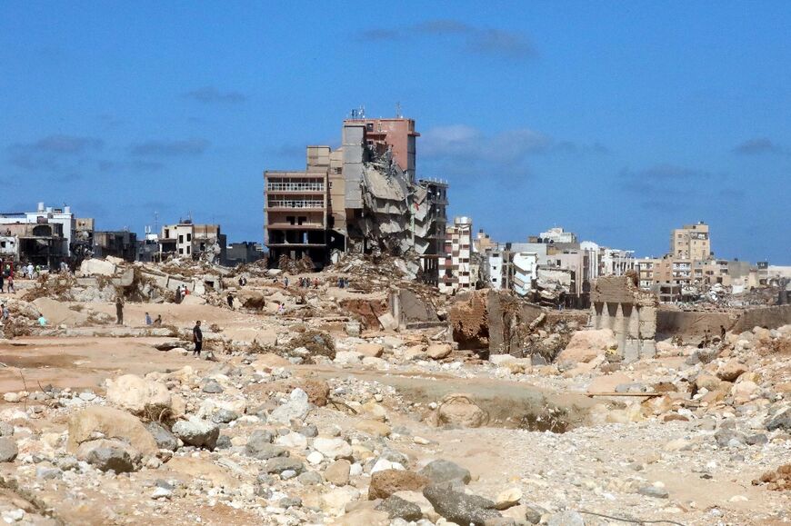 Residents walk amid buildings damaged by floods after the Mediterranean storm Daniel hit Libya's eastern city of Derna