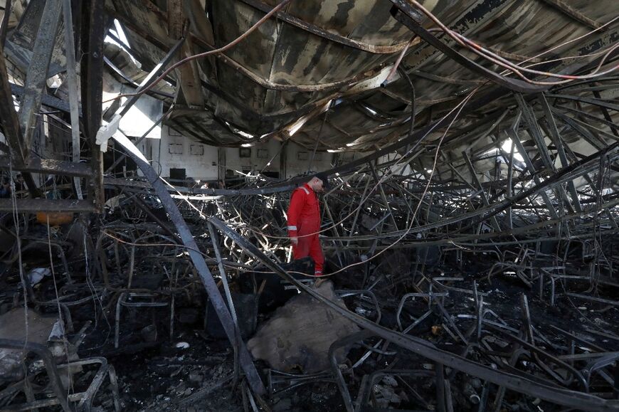 A firefighter inside the charred event hall where a raging fire during a wedding reception killed at least 100 people and injured more than 150 