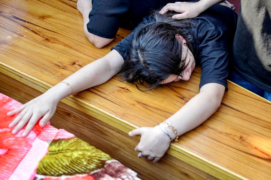 A woman mourns over a coffin during the funeral of those killed in the wedding fire