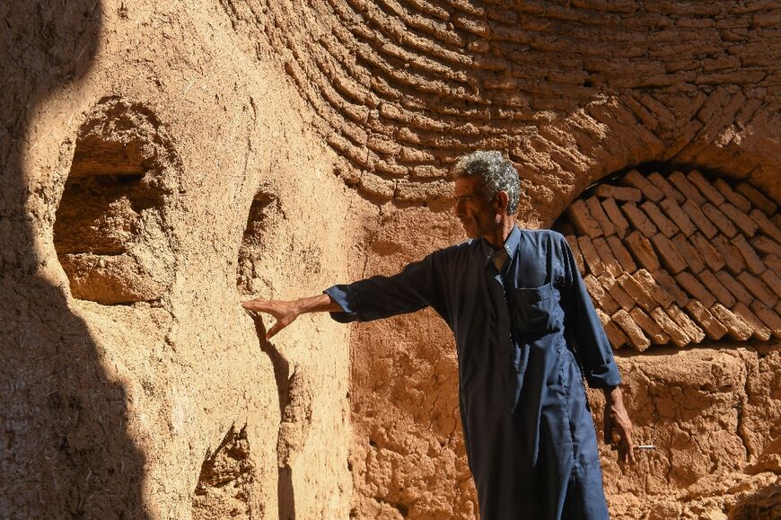 Mahmoud Al-Mheilej, a Syrian resident of the 'beehive' mud houses, inspects the walls of a building in the village of Umm Amuda Kabira in Aleppo's eastern countryside