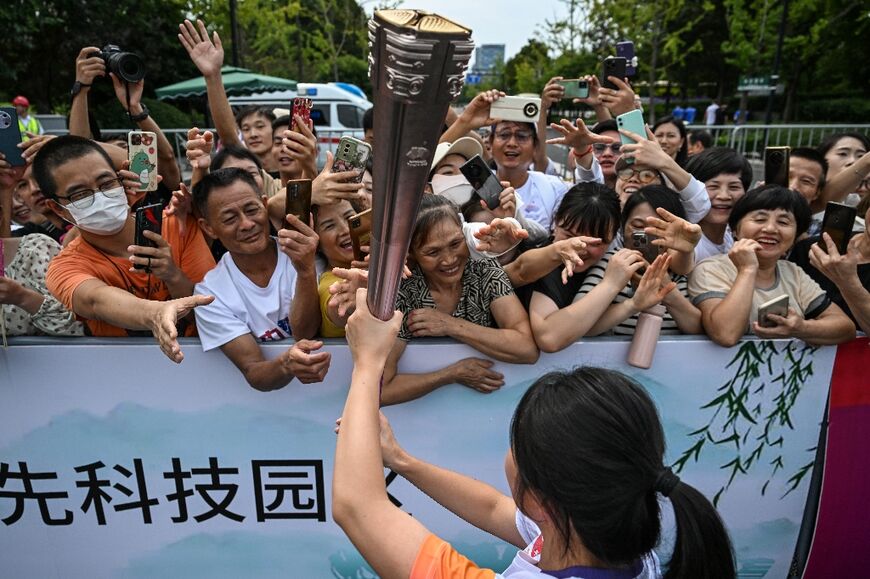 Spectators watch the torch relay of the Asian Games 