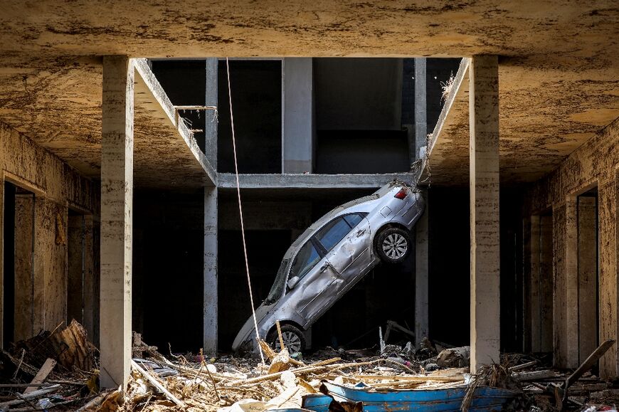 A tilted car sits above debris in Libya's eastern city of Derna 