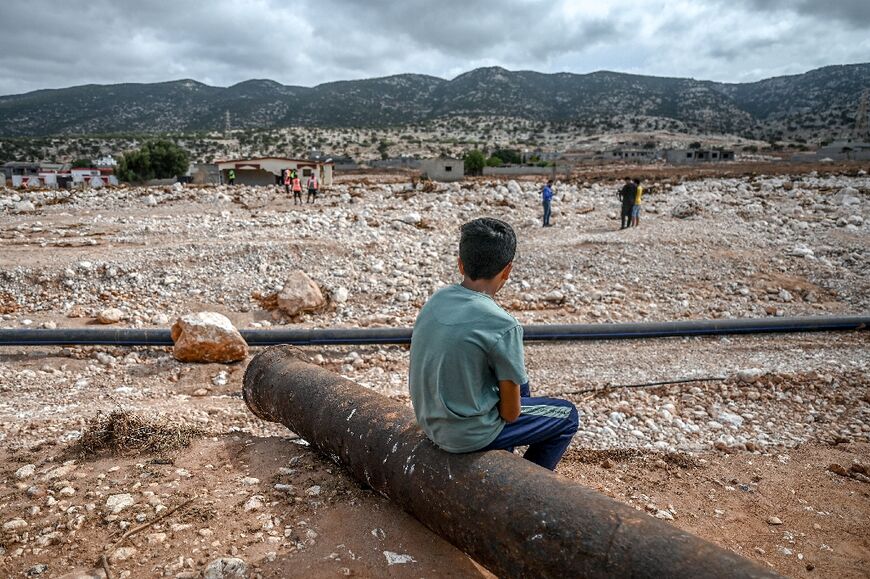 A boy watches as rescue teams search through the rubble in Susa