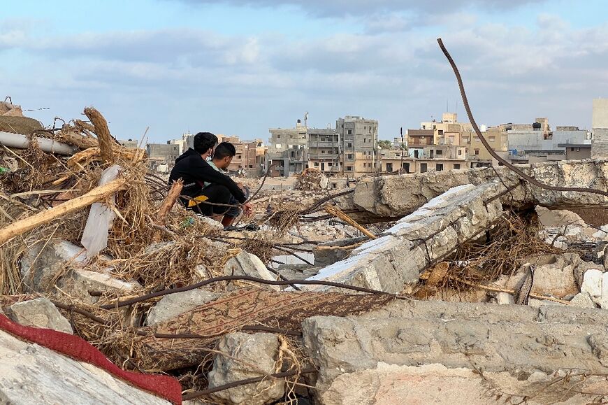 People sit among the rubble in Libya's eastern city of Derna