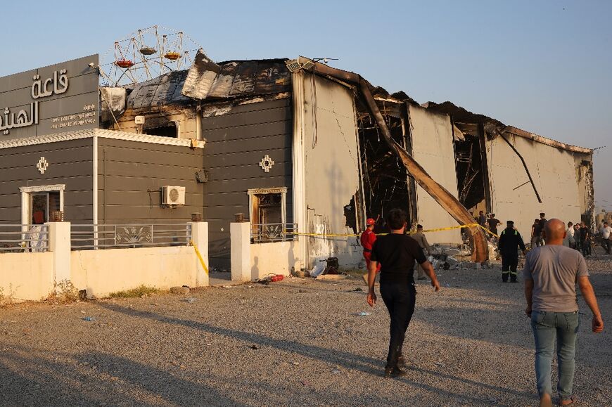 Iraqis walk past the scene of the tragedy in the predominantly Christian town of Qaraqosh, also known as Hamdaniyah