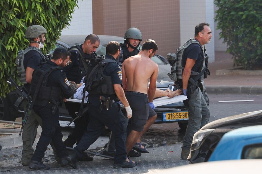 Members of the Israeli security forces carry a person wounded during the rocket attack on Ashkelon