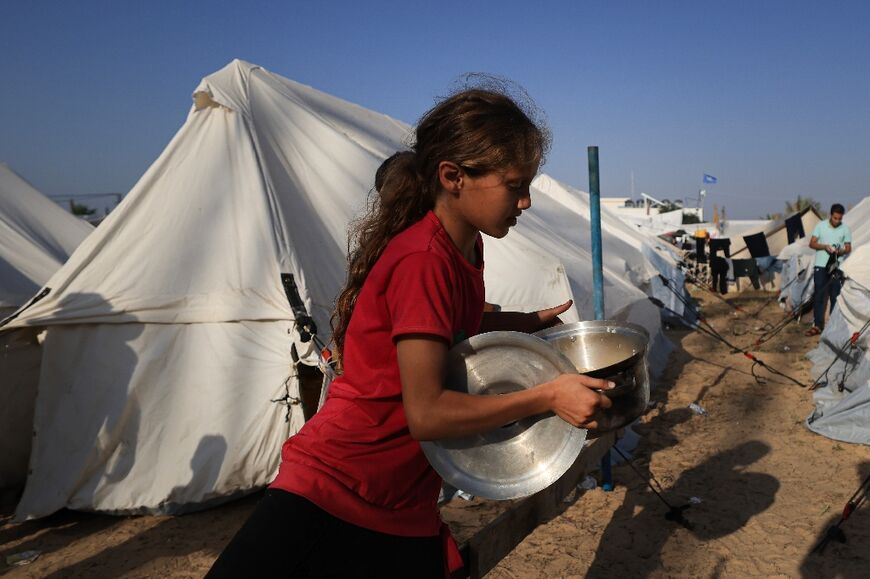 A young girl carries food distributed at a makeshift camp for displaced people in Khan Yunis in the southern Gaza Strip on October 25, 2023