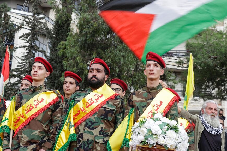 A man waves the Palestinian flag during the funeral of three Hezbollah members killed in intensifying border skirmishes on the Lebanese-Israeli border, in Lebanon's southern city of Nabatieh on October 27, 2023