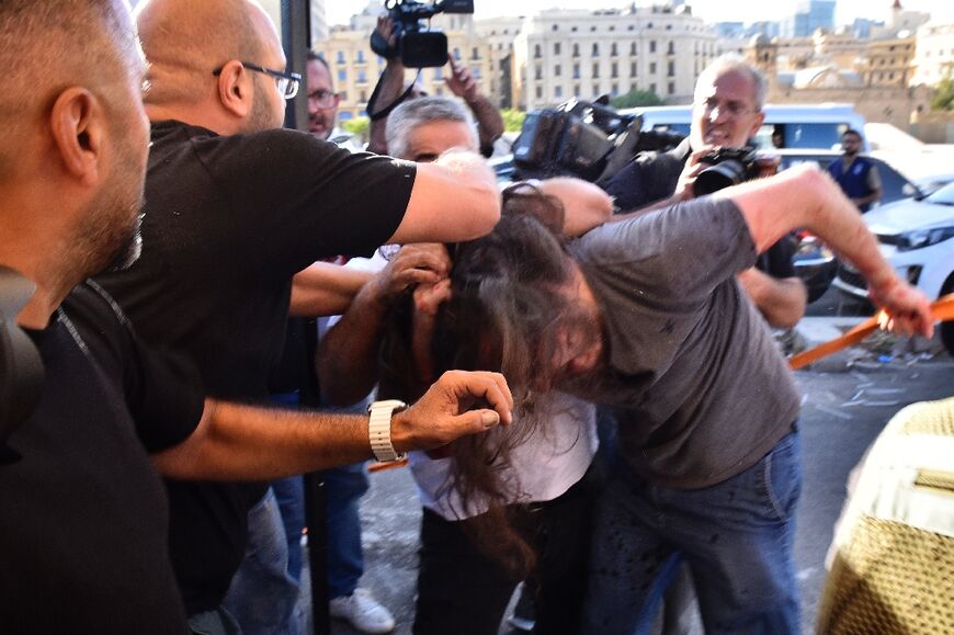 Men attack a participant at a march in support of liberties in Lebanon