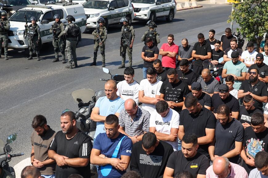 Men below the age set by Israel for entry to Jerusalem's Al-Aqsa mosque compound pray by the roadside outside the walled Old City