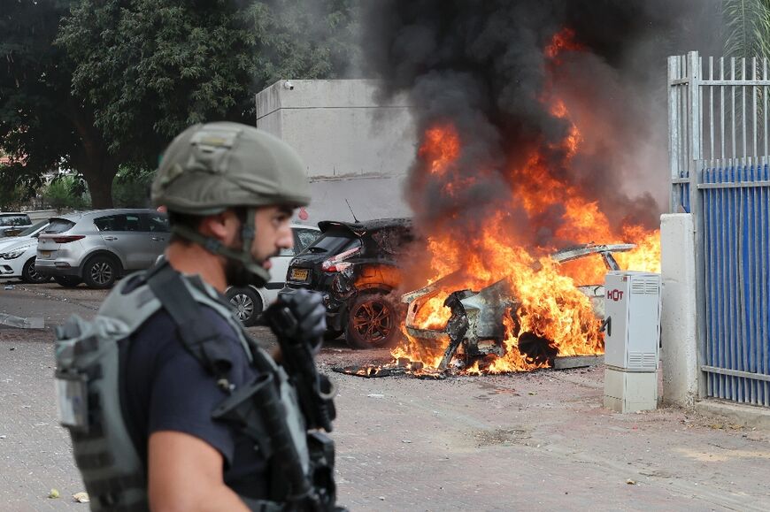 A member of the Israeli security forces near a car hit by a rocket fired from Gaza, in the southern Israeli city of Sderot on October 9, 2023