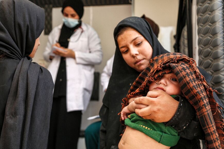 An Iraqi girl carries her brother, who suffers from intestinal colic, for examination in the village of Al-Ayyach