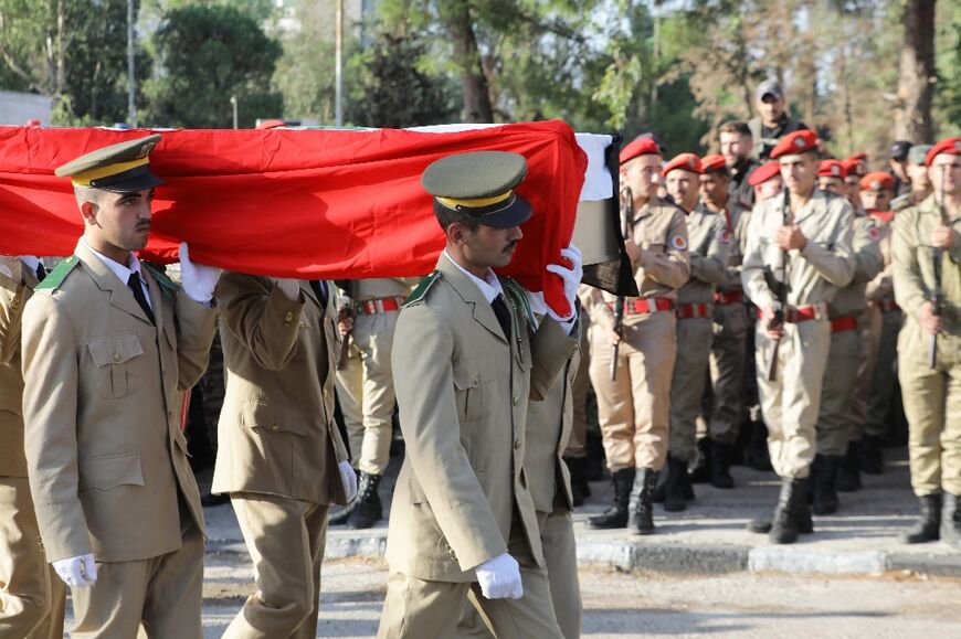 Soldiers carry a casket during the funeral of the victims of a drone attack on a Syrian military academy