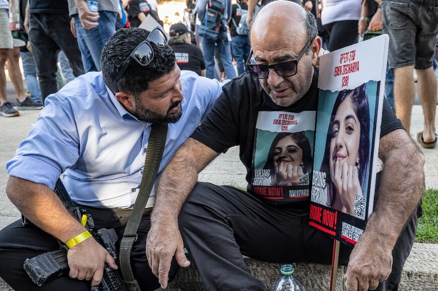 Israeli member of parliament (Knesset) Almog Cohen (L), carrying a rifle, consoles a man