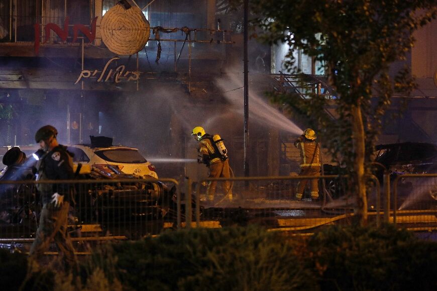 Israeli firefighters douse vehicles following a rocket attack on the northern town of Kiryat Shmona close to the Lebanese border