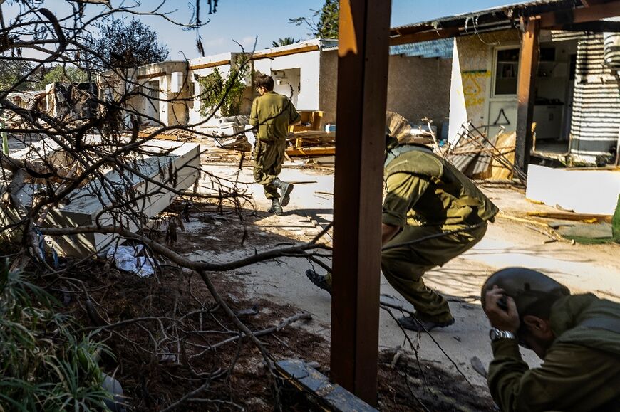 Israeli soldiers take cover as a rocket alert sounds in Kfar Aza during a media tour