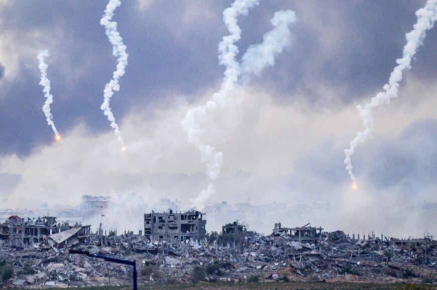 Smoke, seen from southern Israel near the Gaza Strip, billows after an Israeli strike as flares are also dropped over north Gaza 