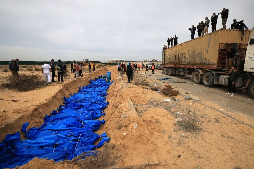 Dozens of blue-wrapped bodies are placed in a mass grave