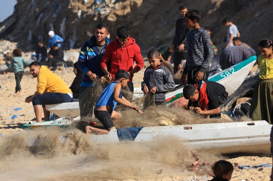 Palestinian children help fishermen untangle nets on Deir el-Balah beach, during a truce in Gaza between Israel and Hamas