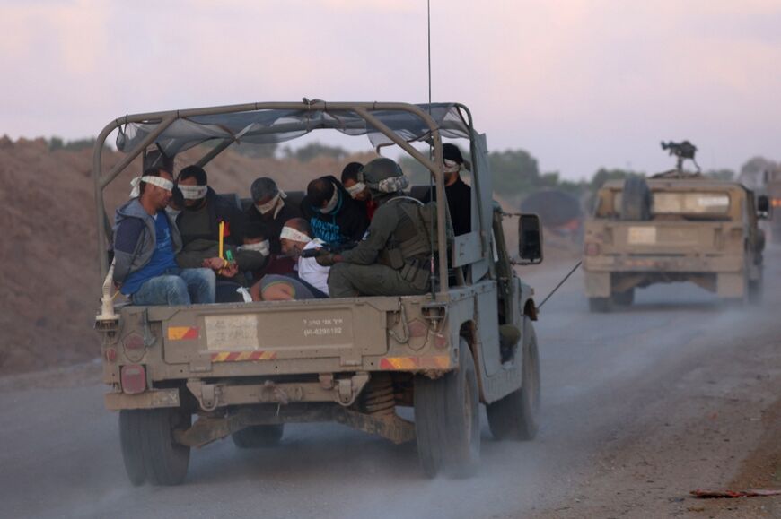 Israeli soldiers transfer detained Palestinians out of the Gaza Strip