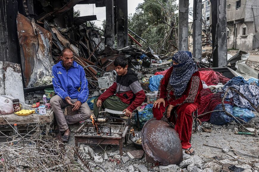 Palestinians cook outside amid the ruins of homes near Abasan in the southern Gaza Strip