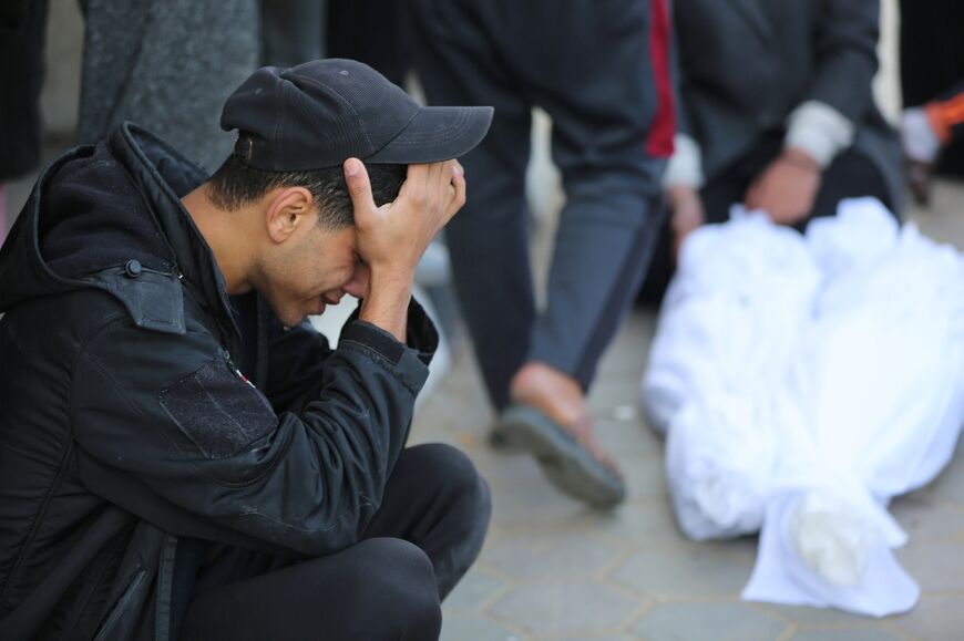 A Palestinian man grieves near the shrouded bodies of relatives killed in an Israeli bombardment on Gaza 