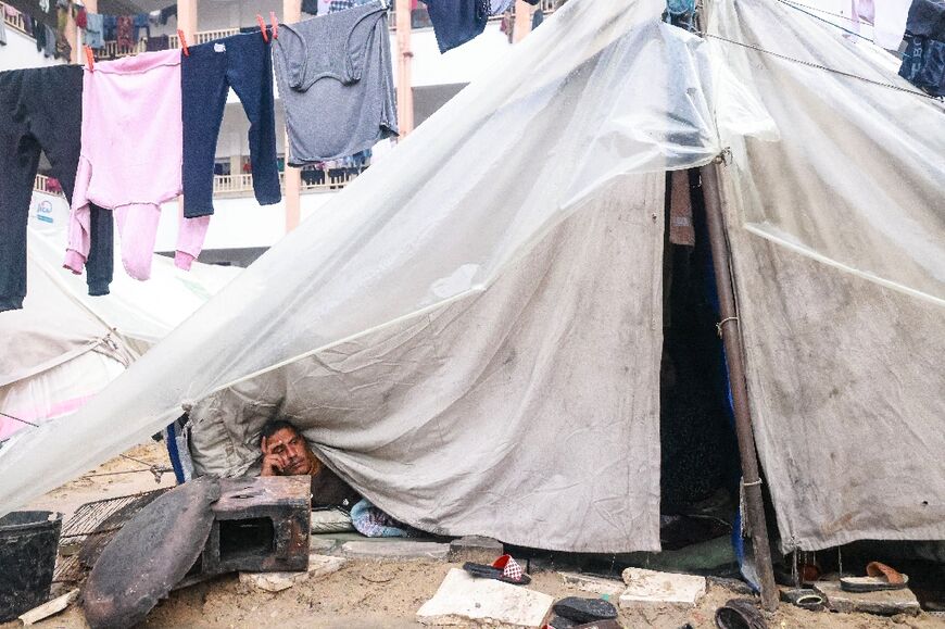 A Palestinian man looks out from his makeshift tent at a camp set up on a schoolyard in Rafah in the southern Gaza Strip 