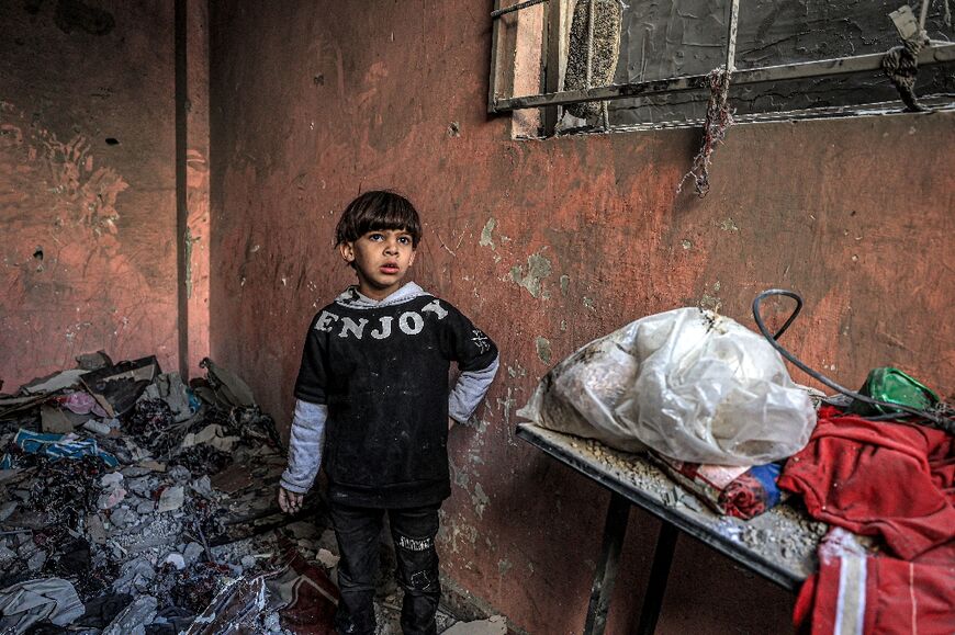 A child stands amid the rubble in a room overlooking a building destroyed by a strike in Rafah in the southern Gaza Strip on December 24, 2023 