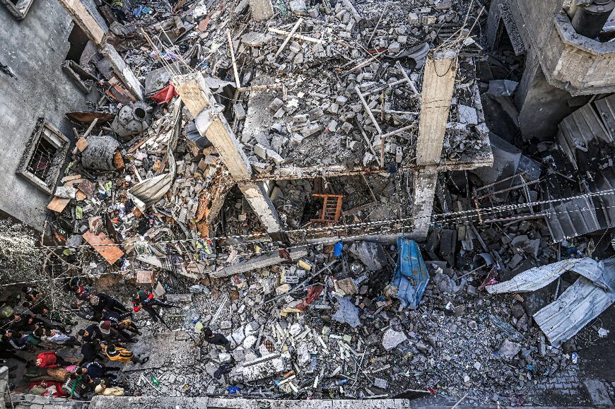 People inspect the rubble of a building destroyed by Israeli bombardment in Rafah in the southern Gaza Strip on December 24, 2023 