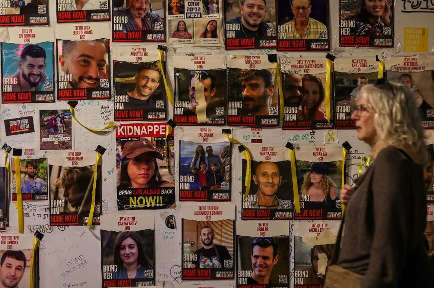 A woman walks past a wall in Tel Aviv showing portraits of Israeli hostages held in Gaza since the October 7 attacks by Hamas