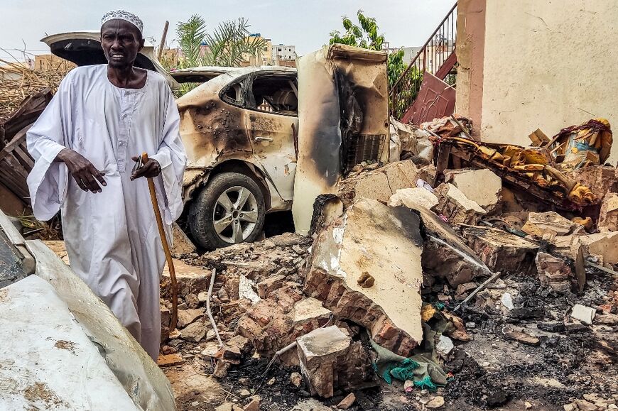 A man walks through the rubble outside a house hit by an artillery shell in the Azhari district of southern Khartoum on June 6, 2023