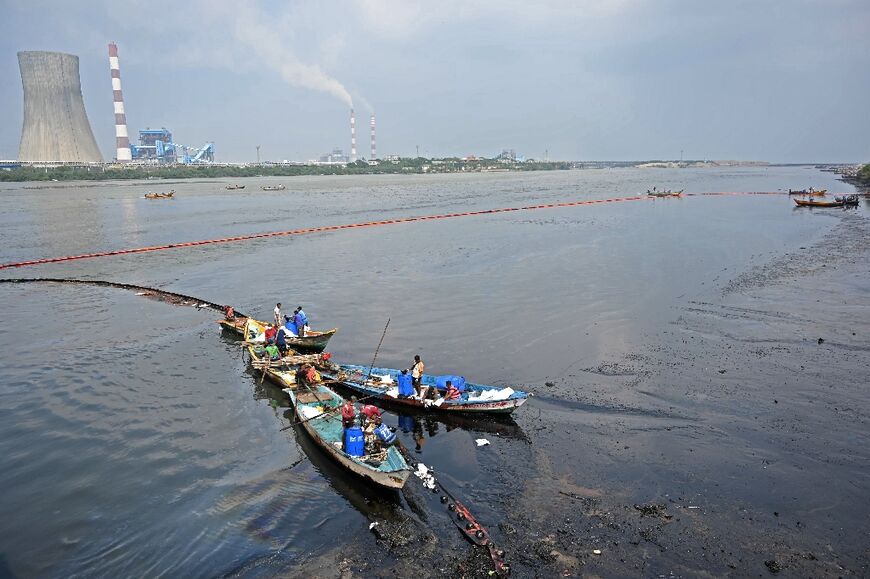 Workers collect oil after it a spill in the aftermath of Cyclone Michaung on the outskirts of Chennai, India