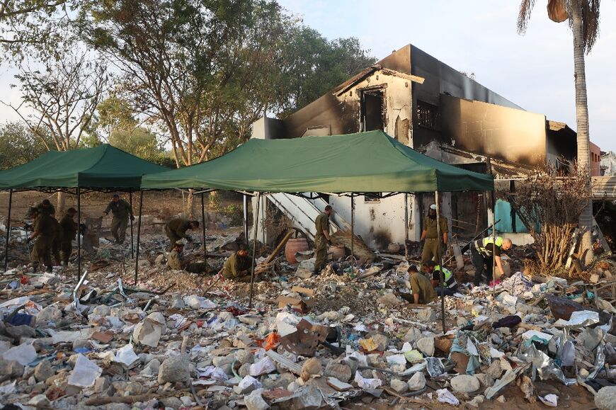 Israeli soldiers and volunteers search through the debris in Kibbutz Beeri on November 12, 2023