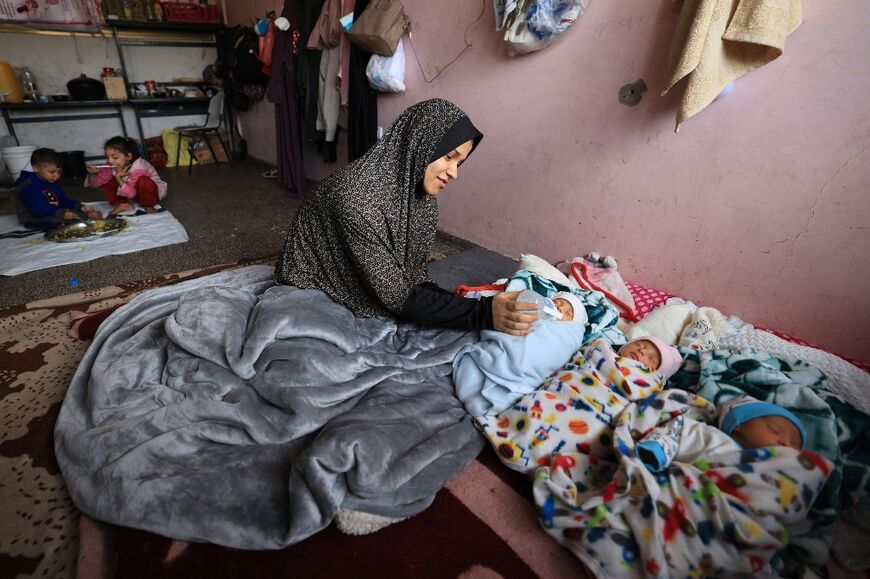 Iman al-Masri, a displaced Palestinian, feeds one of her quadruplets at a school in Deir al-Balah 