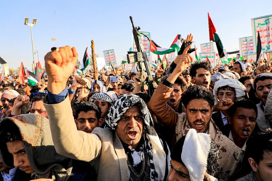 Yemenis brandish a weapon and chant slogans during a march in solidarity with the people of Gaza, in the Huthi rebel-controlled capital Sanaa 