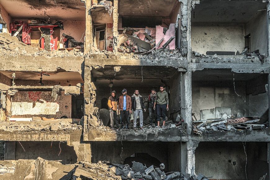 Palestinians check a half destroyed building in Rafah